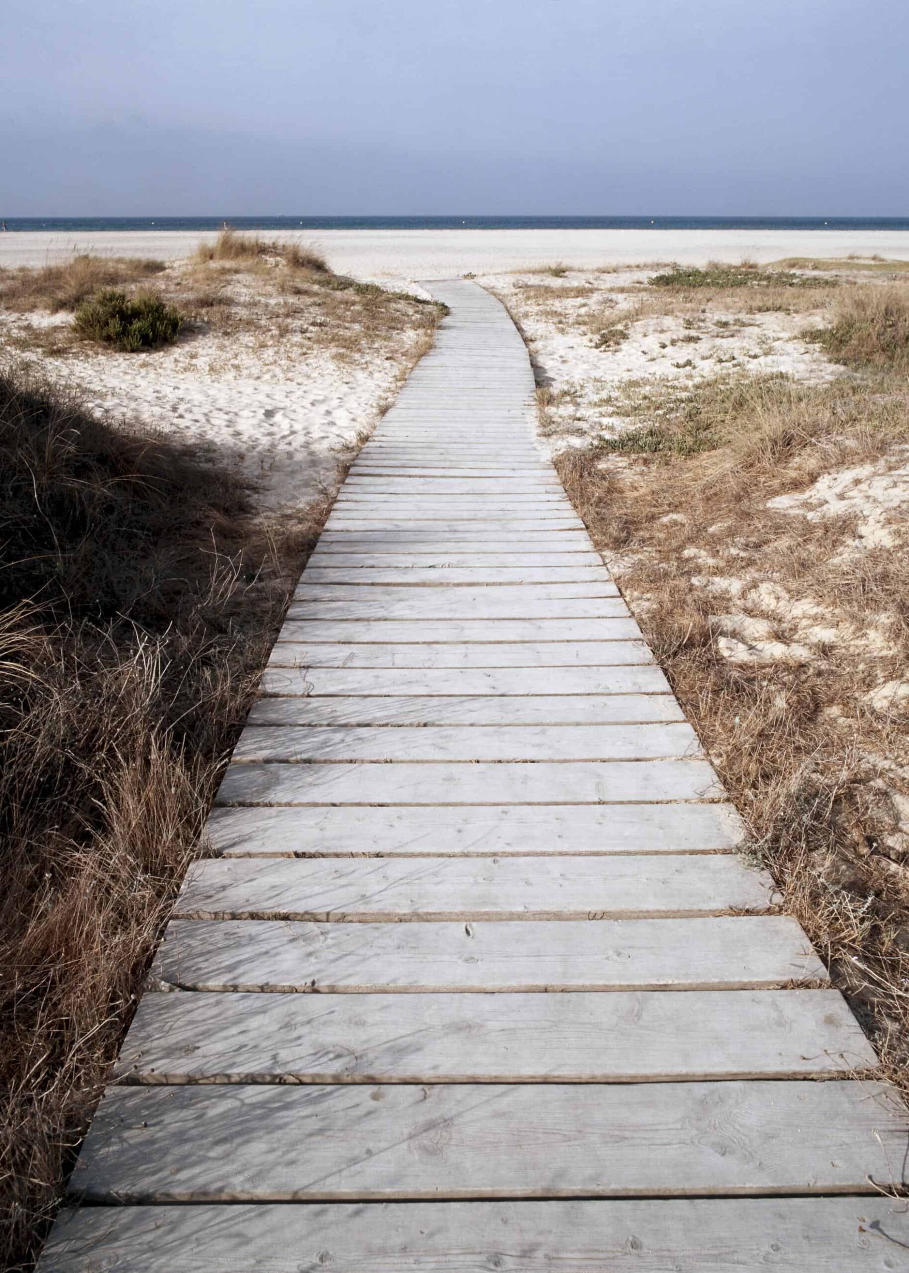 A peaceful boardwalk towards the beach poster